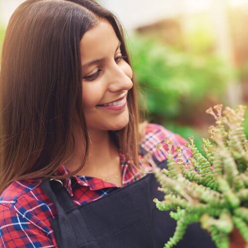 Woman smiling at her flowers in her greenhouse