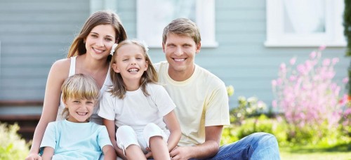 family sitting together smiling outdoors on their porch