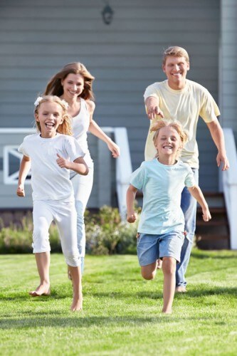 Mom and dad chasing their kids in yard
