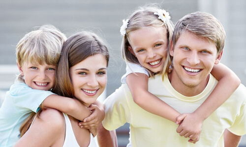 Family portrait with kids riding on parents backs