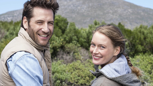 Couple outdoors smiling looking back over shoulders